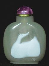 A chalcedony well hollowed cameo carved picture snuff bottle with an amerthyst and metal stopper.  Chalcedony, pale grey with a creamy opaque white skin, simply carved to represent a duck, its head looking back over its shoulders, its eye simply incised, below the duck the waves cut from the grey material; the bottle of flattened form with raised oval foot rim and concave mouth.  Chinese, 1750-1850.  Stopper: amethyst on metal collar.  Provenance: Joan Wasserman collection.  Hugh Moss Ltd, London, 1974.  Height: 6.9cm.  This is a simple but extremely effective rendition of the much loved duck, the contrast within the grey agate is perfect and the whole work of art completed with a minimum of fuss - a little digging here, a little incising there - showing again that less is more.  